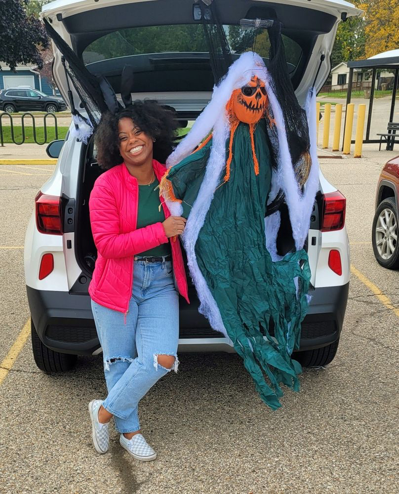 A woman poses with halloween decorations in the trunk of a car